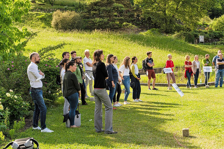 Am Vernetzungstreffen zum Thema "BNE in der Lehre" am 24. Mai 2022 nahmen Dozierende aus neun verschiedenen Fakultäten sowie aus zentralen und weiteren Einrichtungen der Universität teil. Das Foto zeigt die teilnehmenden Dozierenden, wie sie sich auf einer Wiesenfläche im Botanischen Garten nach Fakultäts- bzw. Einrichtungszugehörigkeit positionieren.