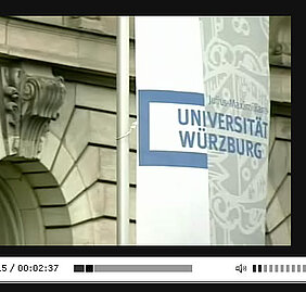 Uni-Fahnen vor dem Hauptgebäude am Sanderring: Ausschnitt aus dem Videoporträt der Uni Würzburg.