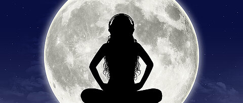 Women meditating in front of a full moon.